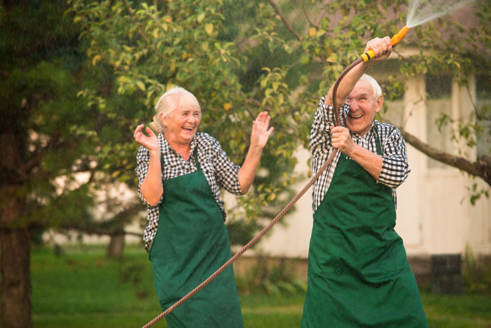 elderly couple outside playing with hose