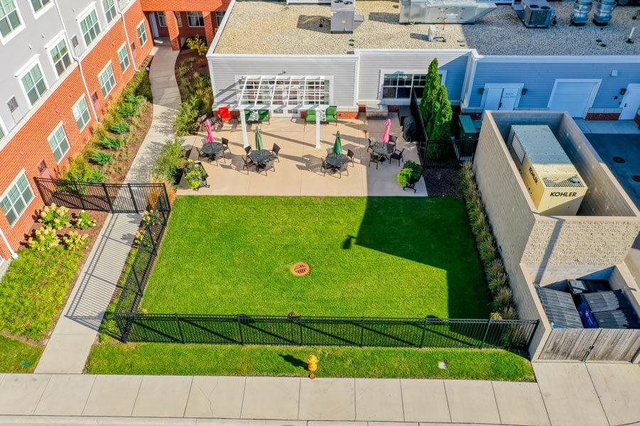 Aerial shot of the patio with tables and umbrellas and a green fenced in area