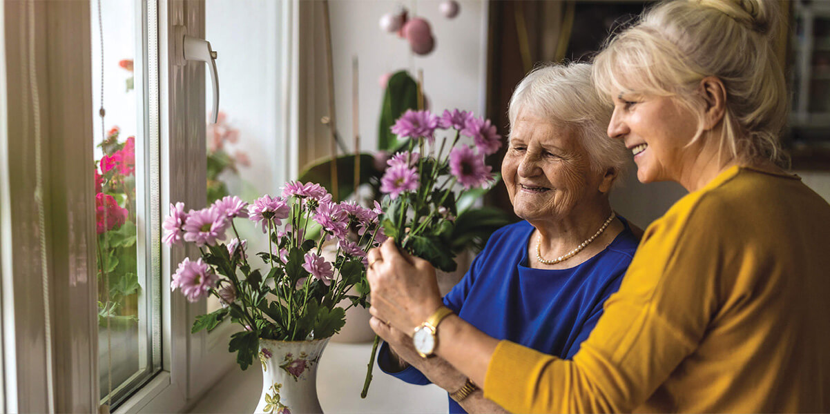 Senior mother and adult daughter pot flowers