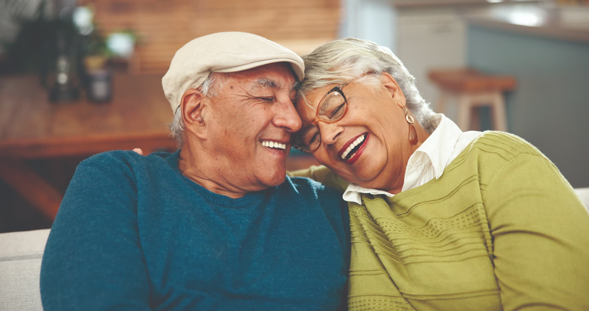 smiling senior couple cuddle on the couch